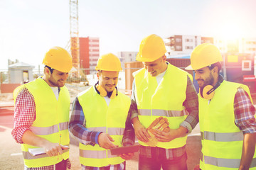 group of smiling builders with tablet pc outdoors