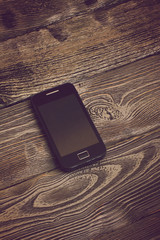 Children's hand takes black phone on wooden table