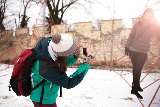 Girl with backpack photographing her friend