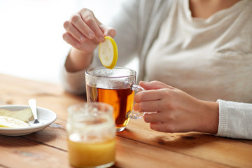 close up of ill woman drinking tea with lemon