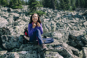 Naklejka na ściany i meble Female hiker rests on the rock in wild reserve