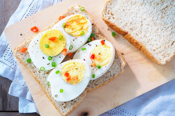 Top view of sliced boiled egg with garnish on wholemeal bread.