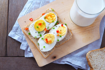 Top view of sliced boiled egg with garnish on wholemeal bread.