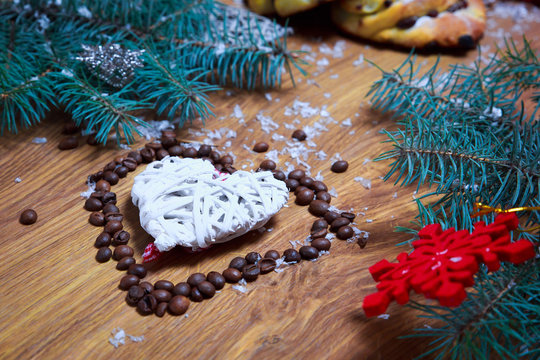 Christmas composition of straw Christmas decorations in white with coffee beans in shape of heart on wooden background