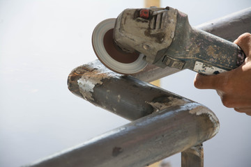 worker cuts a metal pipe with some electric device or appliance