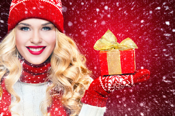Beautyful blond woman with christmas box gift on red background.