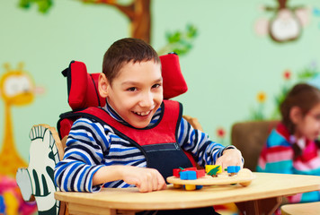 cheerful boy with disability at rehabilitation center for kids with special needs © Olesia Bilkei