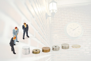 miniature businessmen with coins