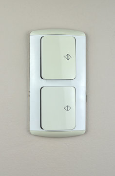 Two white switch plugs on a beige wall