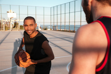 Smiling afro american athlete playing basketball with his friend