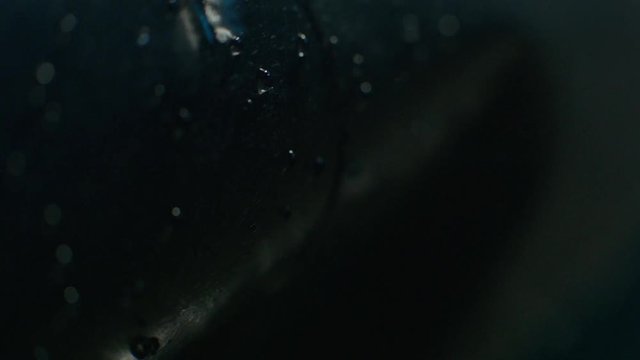 Raindrops falling into the ground. Water drops falls on the black surface. Macro shot, close up, Slow Motion