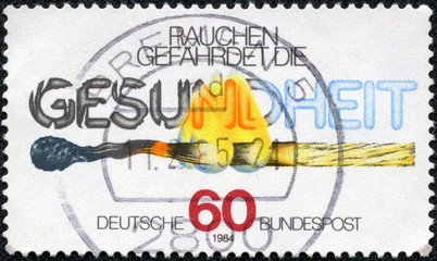stamp printed in Germany shows burning match and the inscription "Smoke endangers the health"