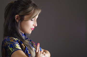 Samurai woman dressed in traditional colorful flower pattern asian silk dress, holding hands together as in praying, seen from profile angle, ninja concept © Fotos 593