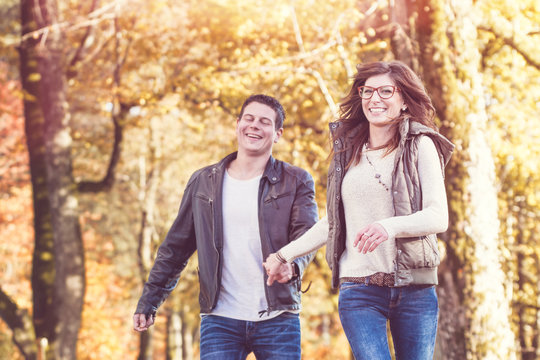 Frau und Mann laufen lachend in den Herbst