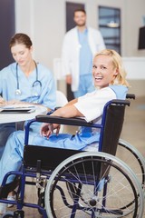 Obraz premium Portrait of cheerful female doctor sitting on wheelchair