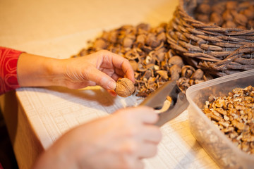 Woman hand shelling fresh walnuts by cracker for christmas sweet