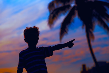 Silhouette of happy little boy play at sunset beach