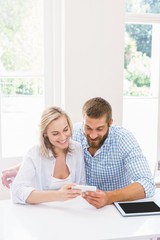 Fototapeta premium Smiling couple using a mobile phone