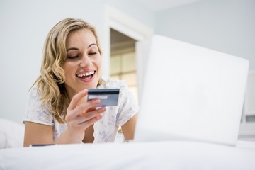 Woman shopping online on bed
