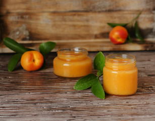 Apricot jam in small glass jars with fruits, selective focus