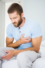 Fototapeta premium Young man having chest pain in bed