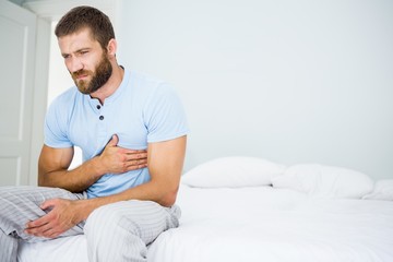 Young man having chest pain on bed