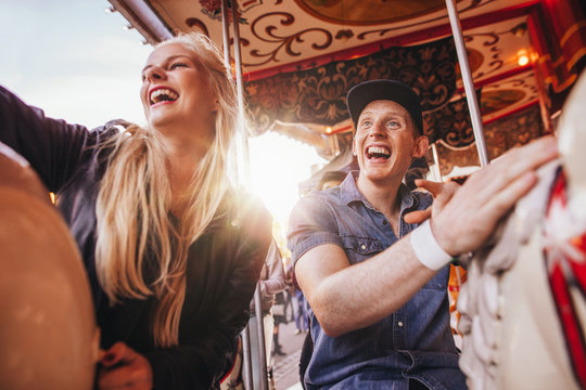 Smiling couple on carousel at fairground