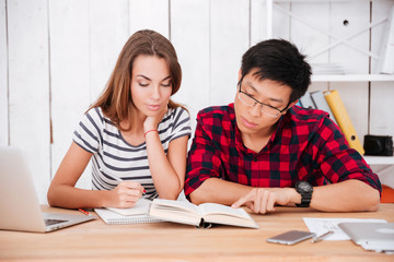 Students learning education material in classroom while looking at book