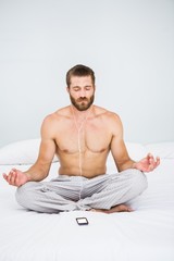 Fototapeta premium Man doing yoga while listening to music on bed