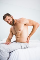 Man suffering from back pain on bed