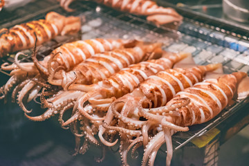 Fresh Squid on skewers is being grilled by a street vendor in Thai street night market.Thai style food