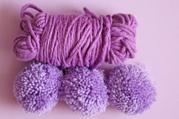 Fototapeta na wymiar three woolen pompoms on a purple background