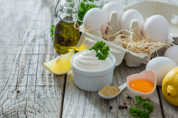 Obraz na płótnie Canvas Mayonnaise sauce and ingredients on wood background