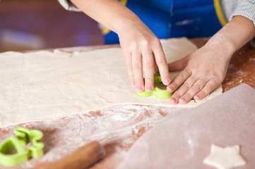 hands of a child who is preparing cookies in the kitchen with flour and dough