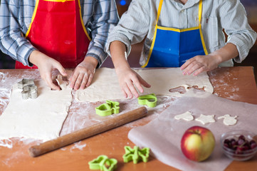 hands of a child who is preparing cookies in the kitchen with flour and dough