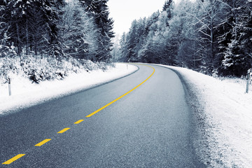 Empty country road in snowy forest in winter 