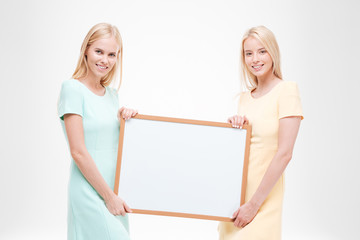 Two young women holding white blank desk