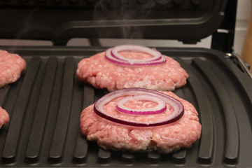 onion rings lie on a piece of meat in the grill