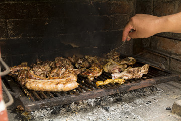 Hand with fork arranging meat on barbecue