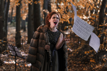 Young emotional woman throwing away the musical sheets and holding an oboe in hand