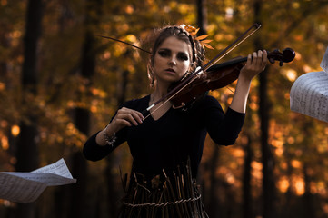 Young woman fiddle over the music notes flying away and fall park background