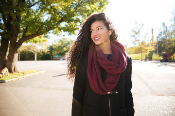Happy young dark skinned curly woman wearing scarf smiling