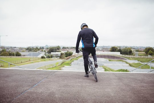 Cyclist standing with BMX bike at starting ramp