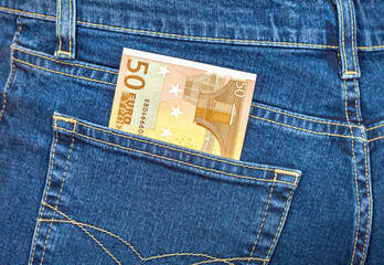 Banknote 50 euro sticking out of the blue jeans pocket. Money fo