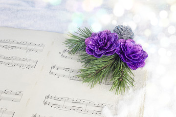 Christmas decoration with pine tree, purple flower and musical score on a white snow background.