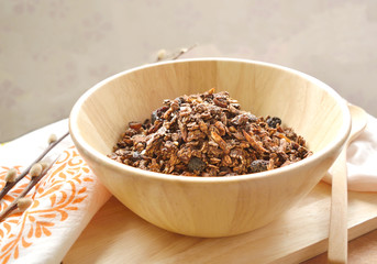 Home made cocoa granola with oats, chia seeds, flax seeds, almonds and raisins on a wood bowl