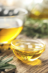 Olive oil  in the glass bowl on wooden table  vertical