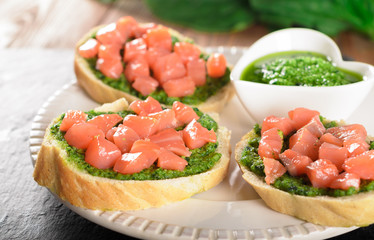 Bruschetta with fresh salmon and pesto sauce and white sauceboat