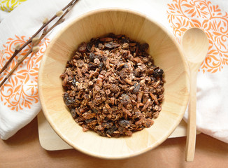 Home made cocoa granola with oats, chia seeds, flax seeds, almonds and raisins on a wood bowl