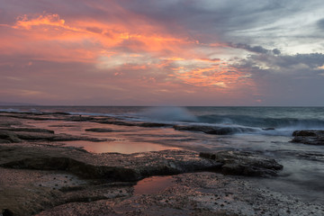 Fototapeta na wymiar Vivid orange and soft blue colors after sunset over the rocky coastline of western Galilee